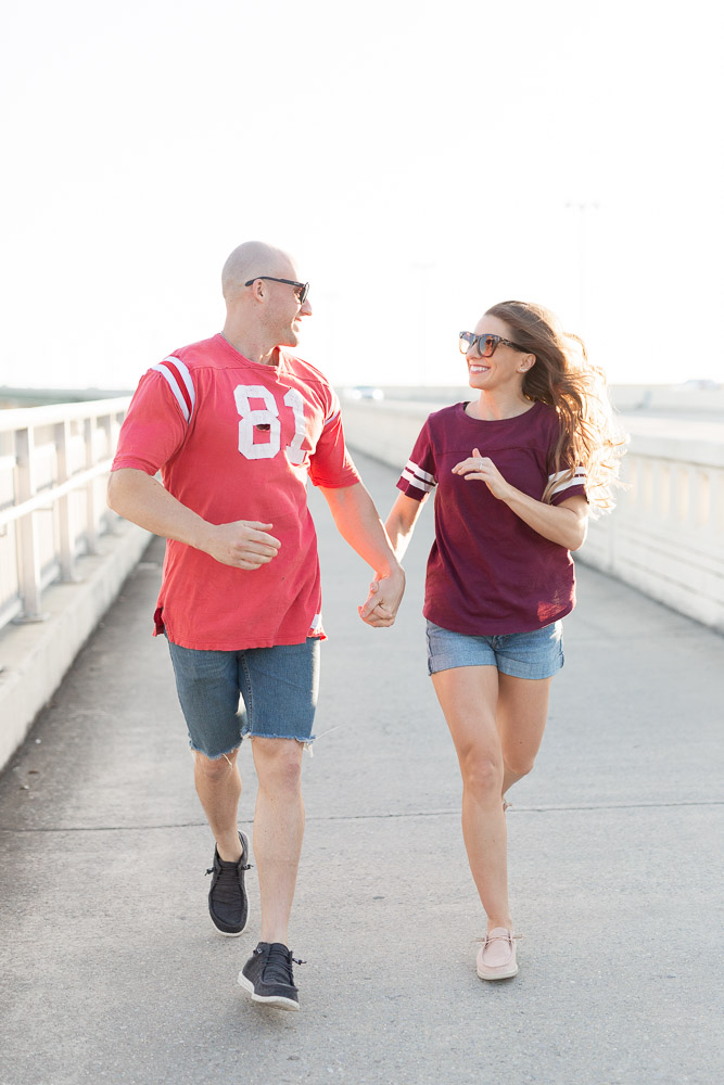 Engaged Couple Running on Ocean Springs Bridge | Engagement Session